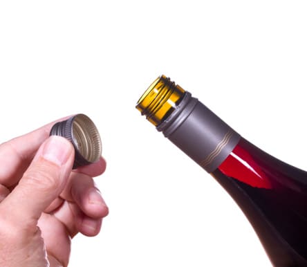 Red or rose wine in screw top wine bottle isolated against white with hand holding the cap by the neck of bottle