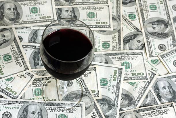 A glass of red wine on a background of $100 bills