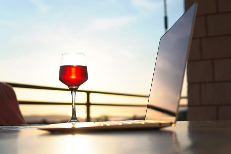 Laptop,Next,To,A,Glass,Of,Wine,During,Sunset
