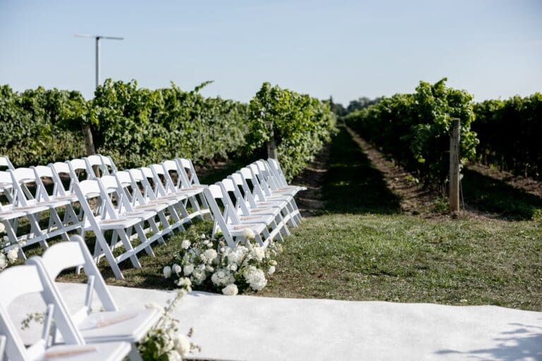Wedding,Ceremony,Isle,And,Flower,Arrangements,With,Folding,White,Chairs