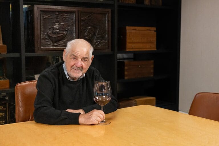 Marvin R. Shanken seated at a boardroom table holding a glass of red wine