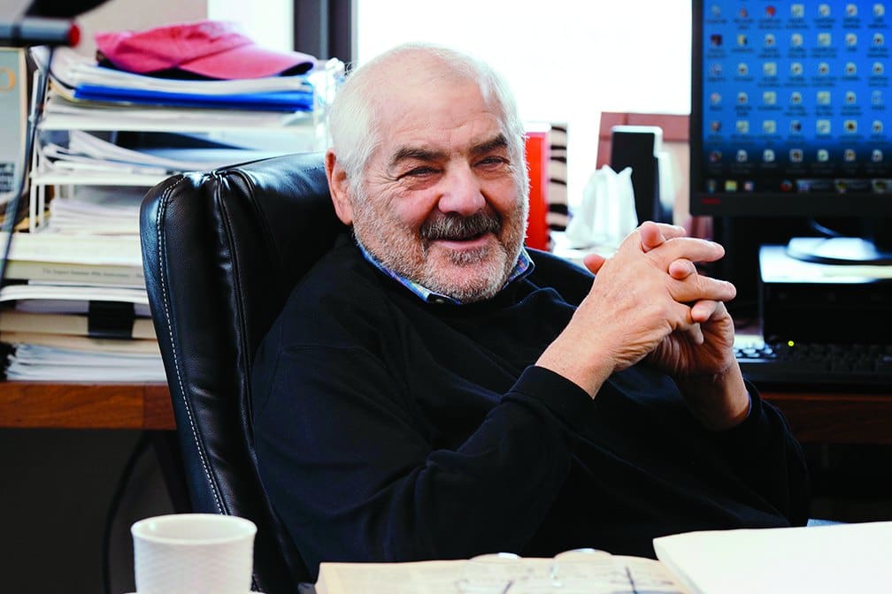 Marvin R. Shanken smiling at his desk in his office