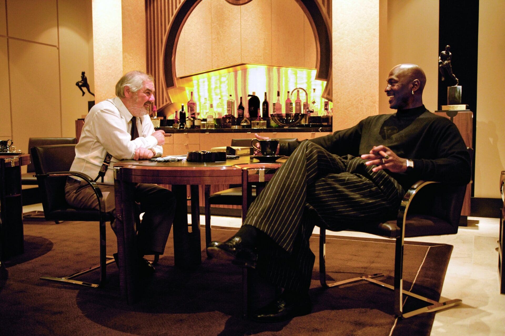 Marvin R. Shanken and Michael Jordan seated at a table smoking cigars