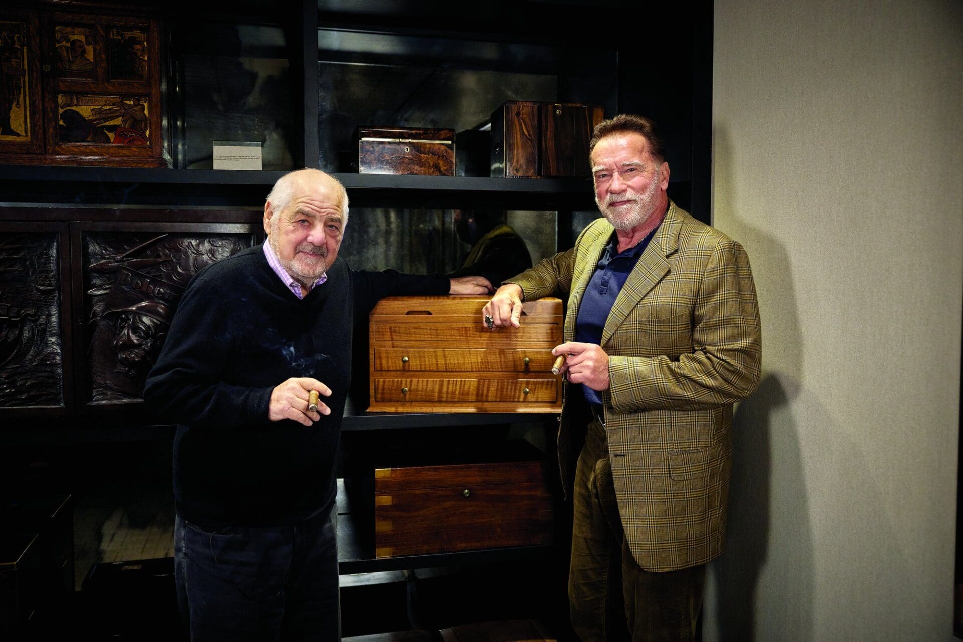 Marvin R. Shanken and Arnold Schwarzenegger standing beside a wooden humidor